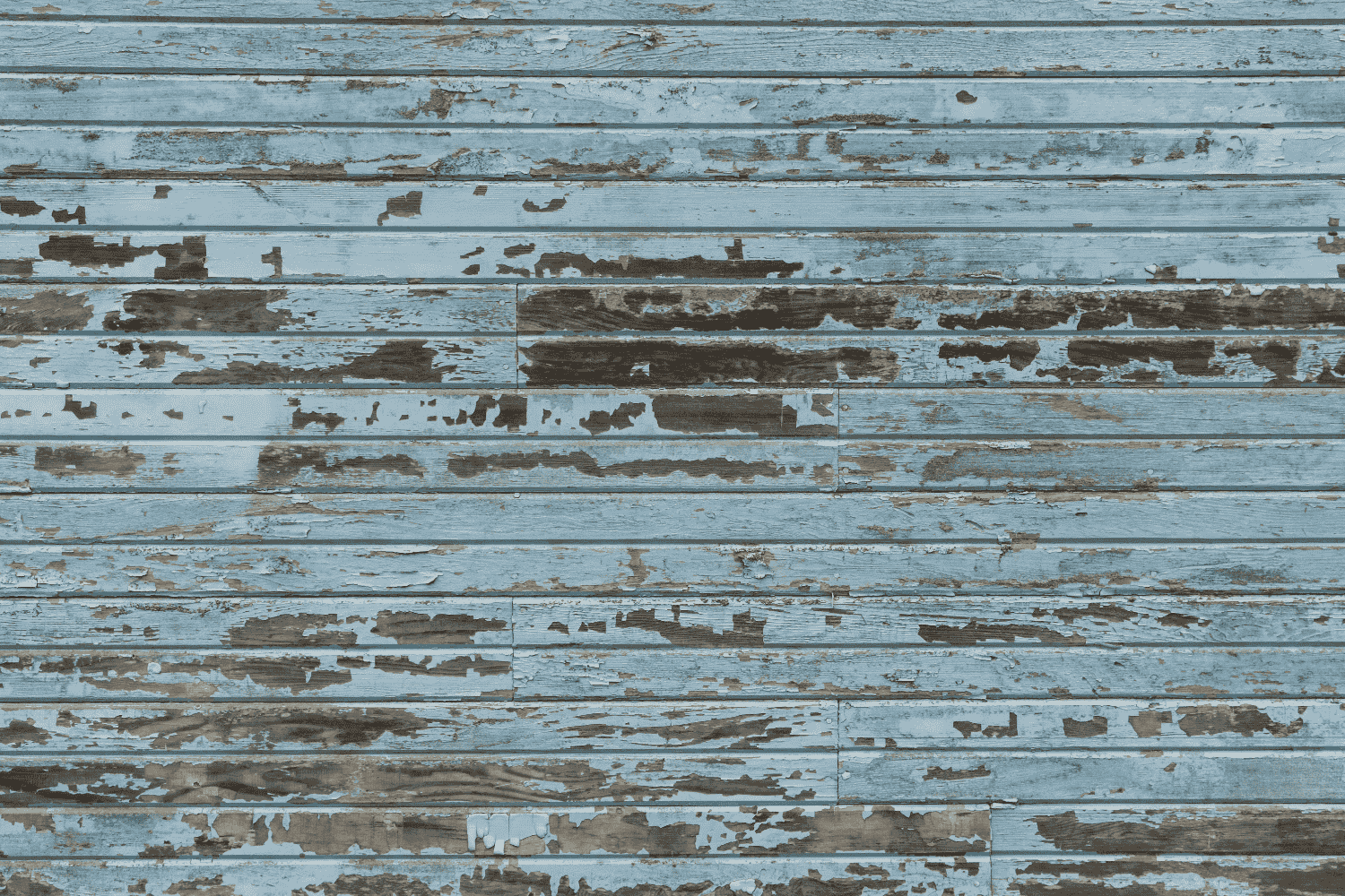 A close up view of wood siding on a house, showing signs of wear and rot.