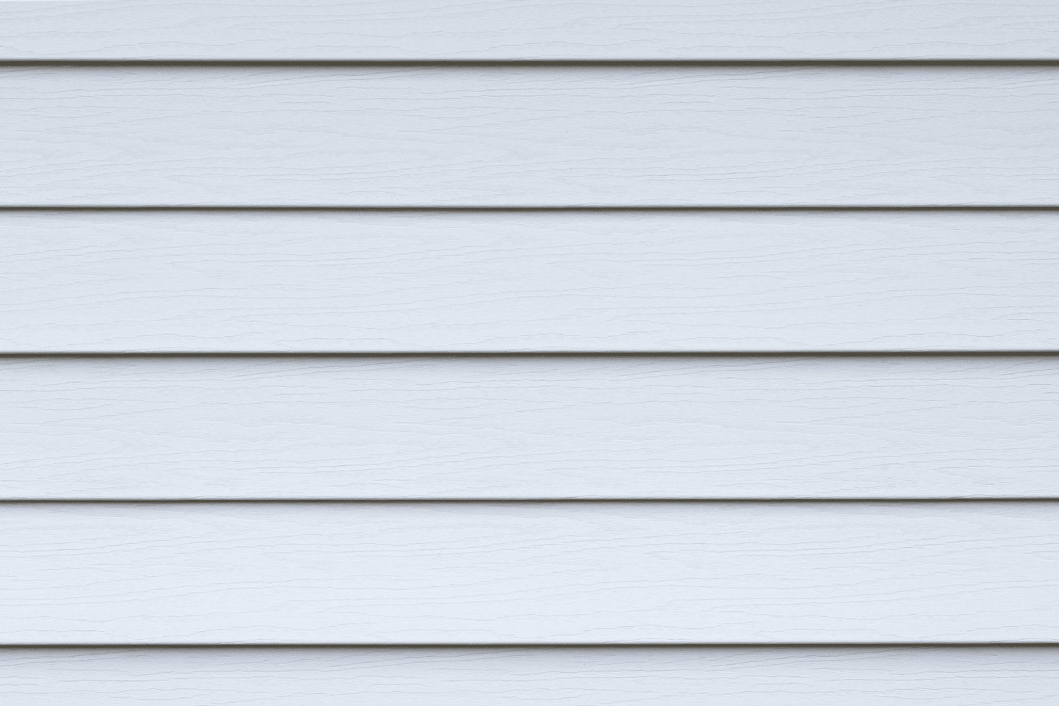 A person applying exterior paint to newly installed wood siding.