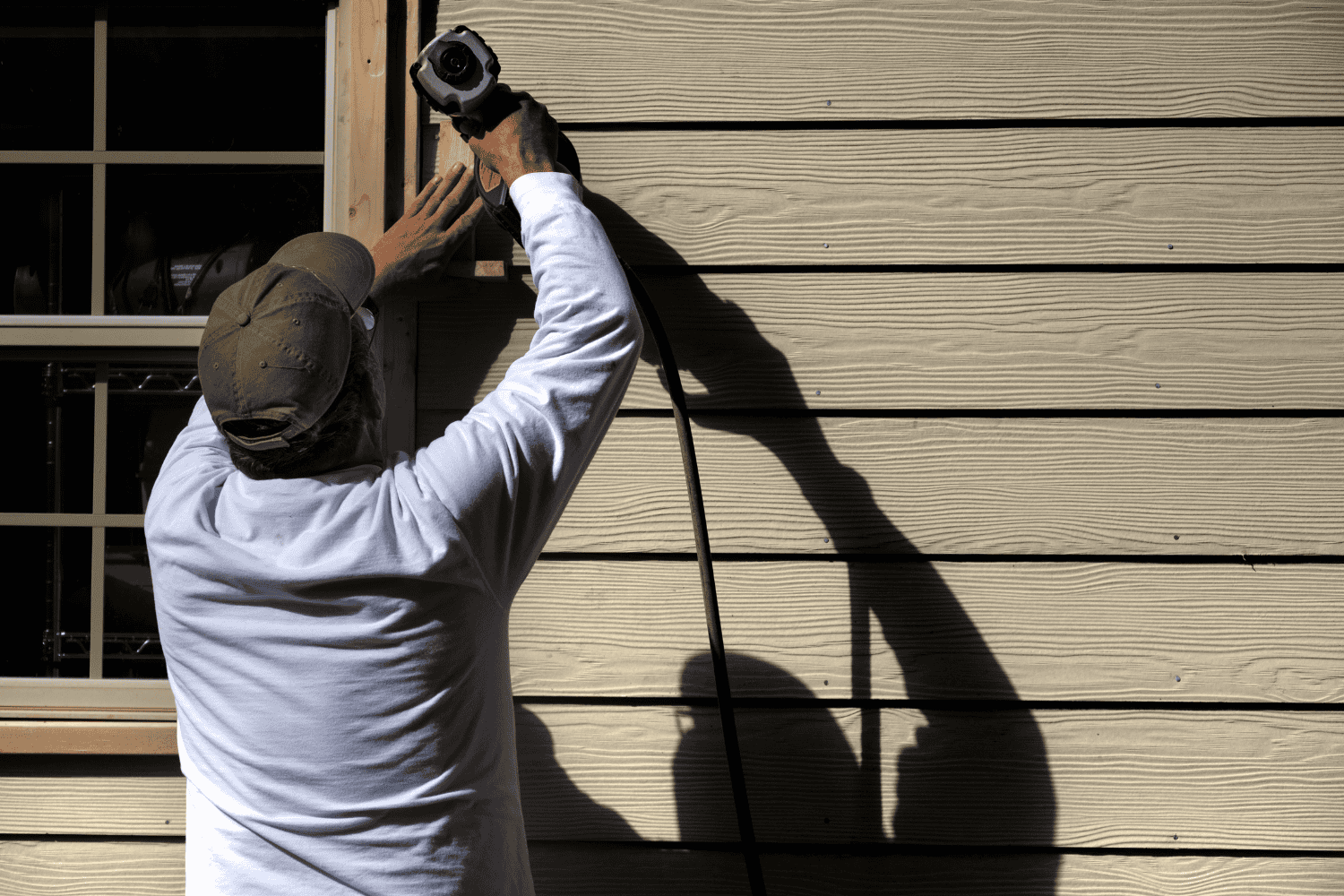 A variety of tools laid out for wood siding repair, including a utility knife and a putty knife.